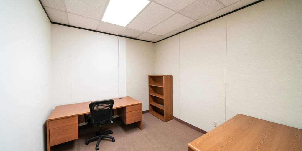 an empty room with a desk and a book shelf